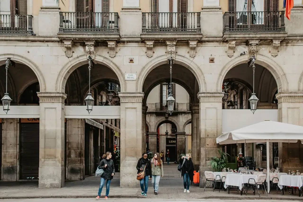 Sétálók egy barcelonai árkádsor előtt